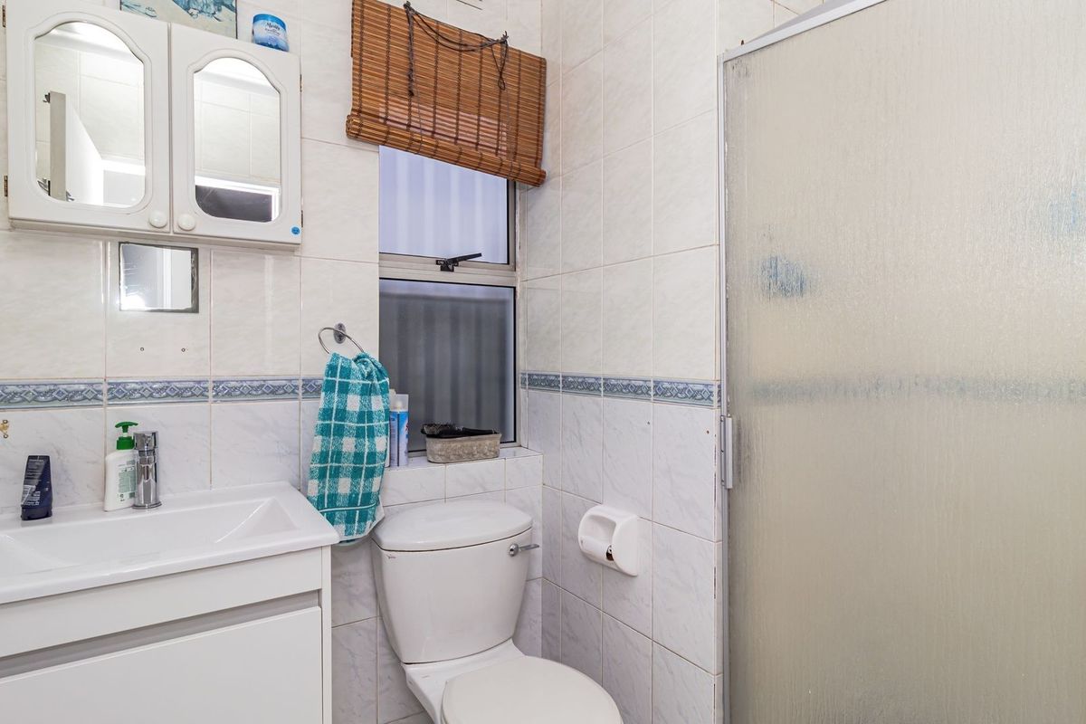 A compact bathroom featuring a vanity unit, a standard toilet, and a shower enclosure with a frosted glass screen.
