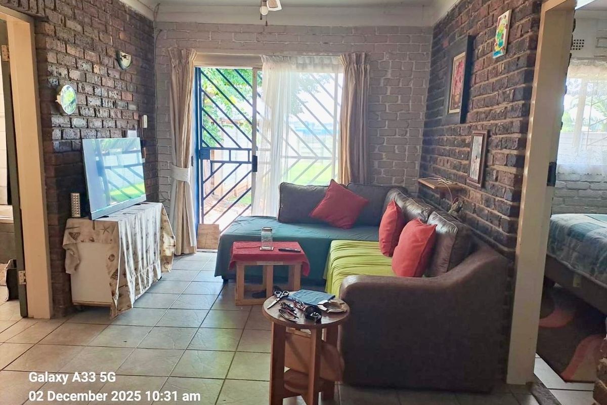 A living room featuring exposed brick walls, tiled flooring, and a sliding glass door providing access to the exterior.
