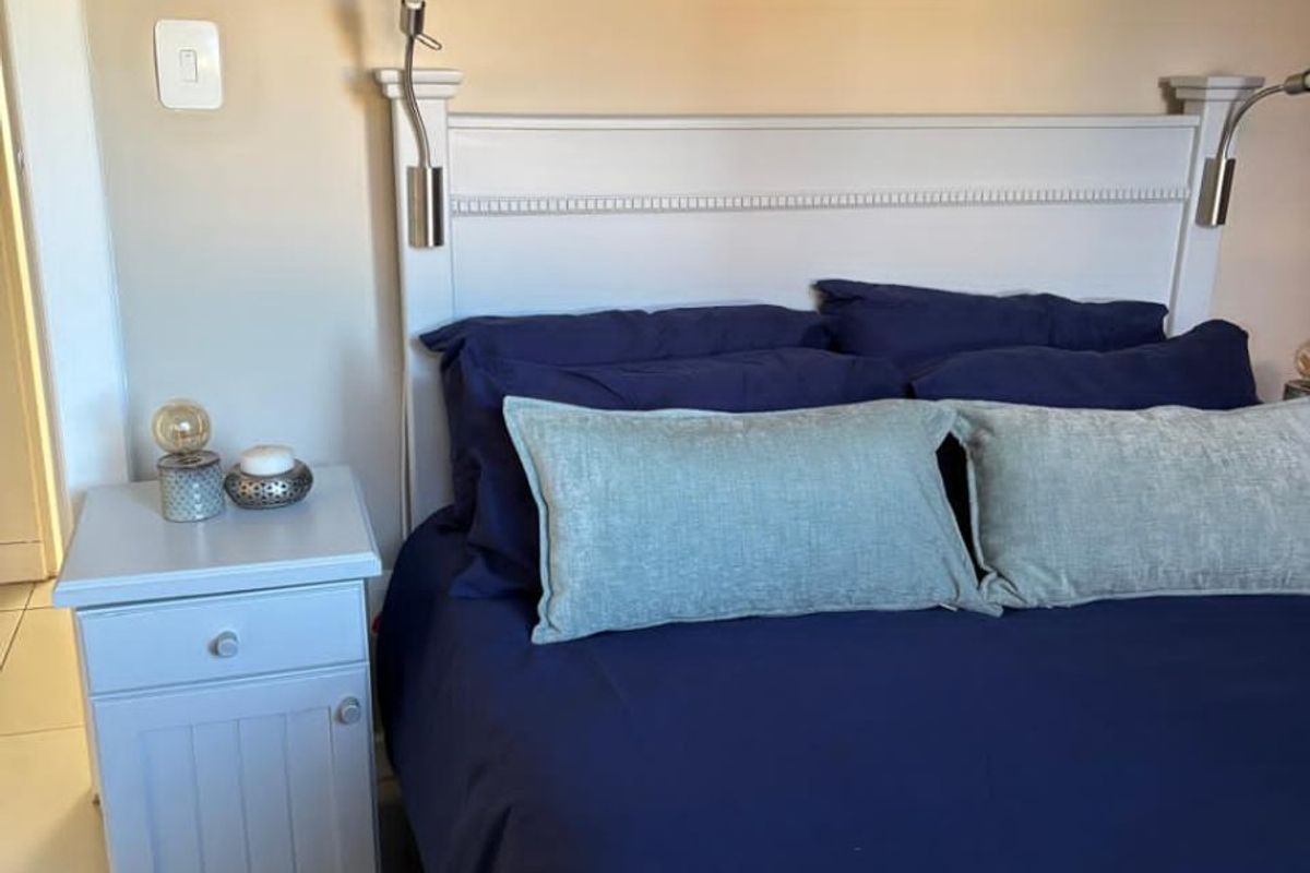 A bedroom featuring tiled flooring and integrated wall-mounted reading lights above the headboard area.