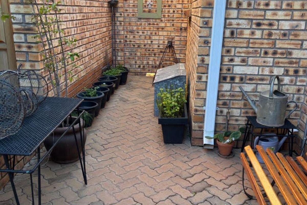 A narrow paved side courtyard featuring face-brick walls and a functional downpipe, providing a private outdoor utility space.