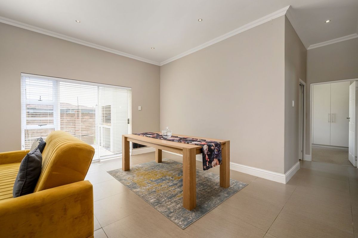 A bright living area featuring neutral tiled flooring, recessed downlighting, and a sliding glass door providing access to the exterior.