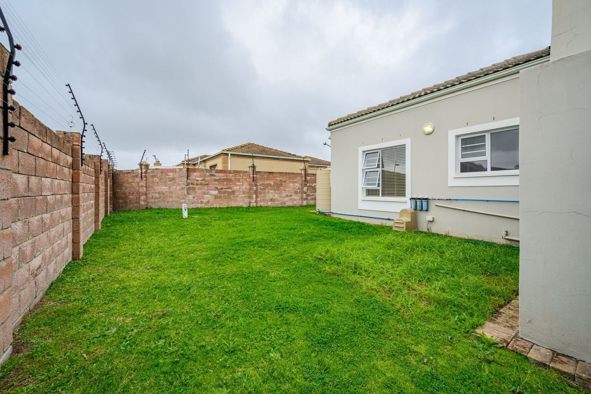 A private rear garden featuring a lawn, brick boundary walls with electric fencing, and access to the side of the house.