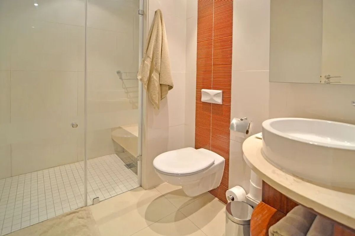 Modern bathroom featuring a glass-enclosed walk-in shower, wall-mounted toilet, and a contemporary vessel sink vanity with decorative tiled accent wall.