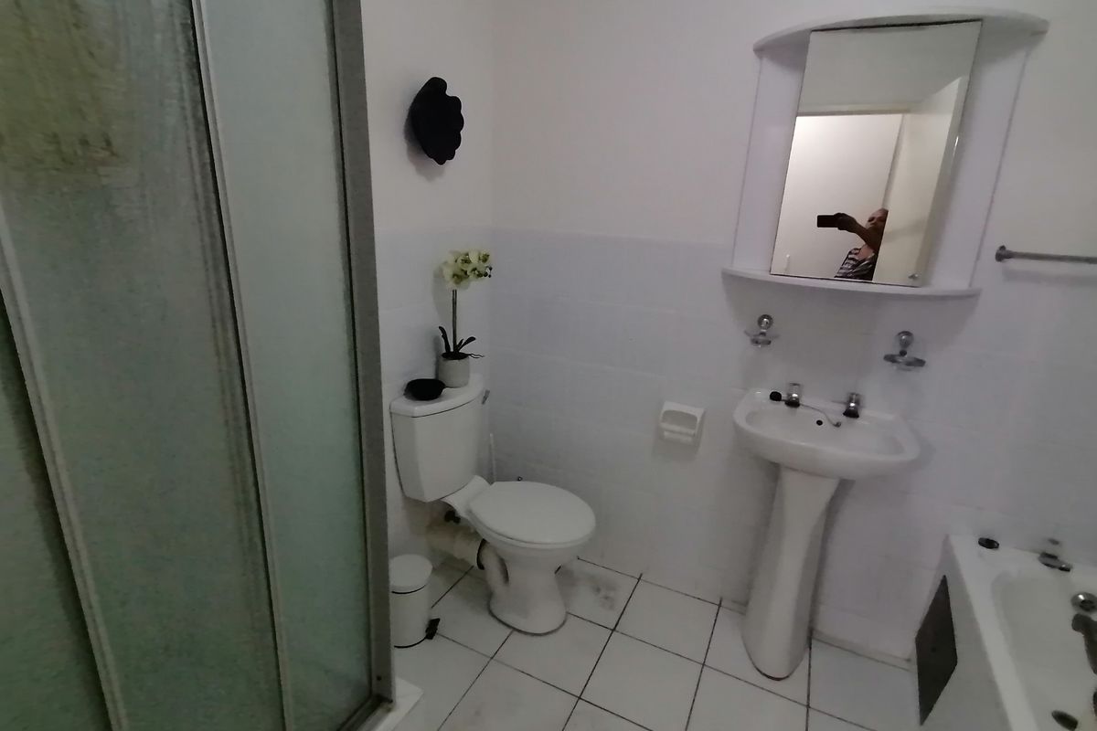 A functional bathroom featuring a pedestal basin, a toilet, and a separate shower enclosure with white tiled flooring.