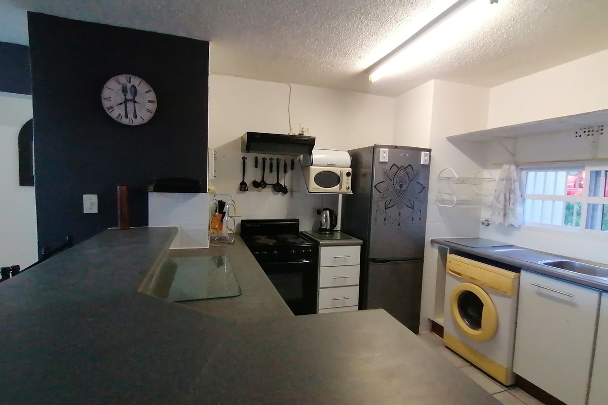 Functional kitchen featuring a breakfast bar, built-in oven with extractor fan, stainless steel sink, and dedicated space for laundry appliances.