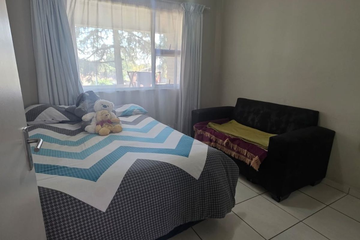 A bedroom featuring tiled flooring and a large window that allows for natural light.