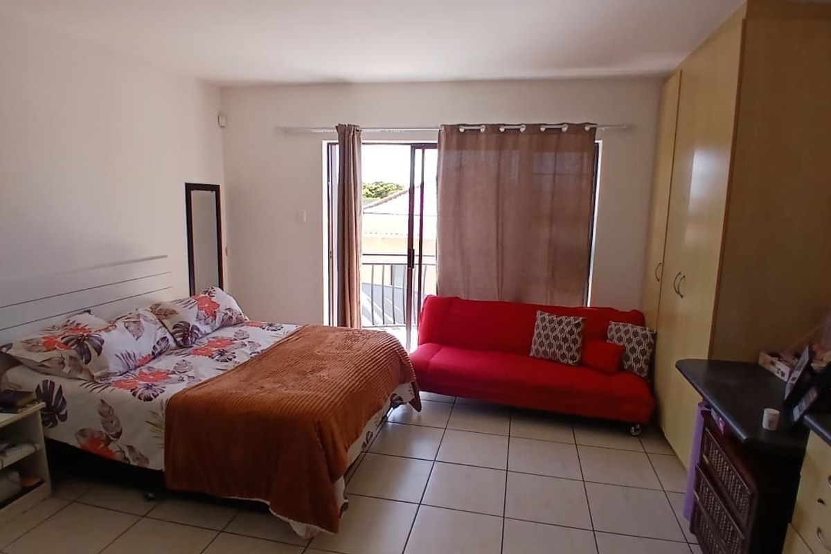 A bedroom featuring tiled flooring, built-in cupboards, and sliding glass doors leading to a balcony.