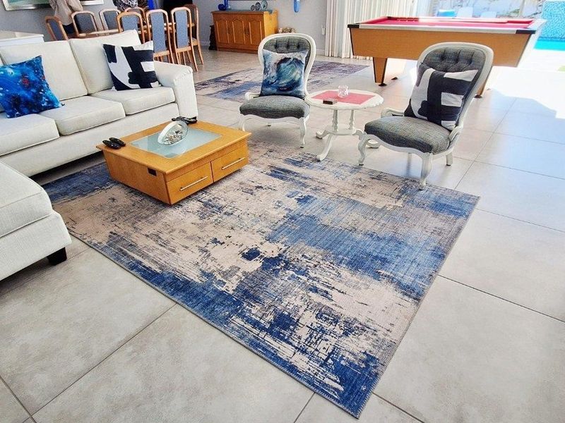 Spacious open-plan living area featuring large format floor tiles and seamless flow to an outdoor patio and swimming pool area.