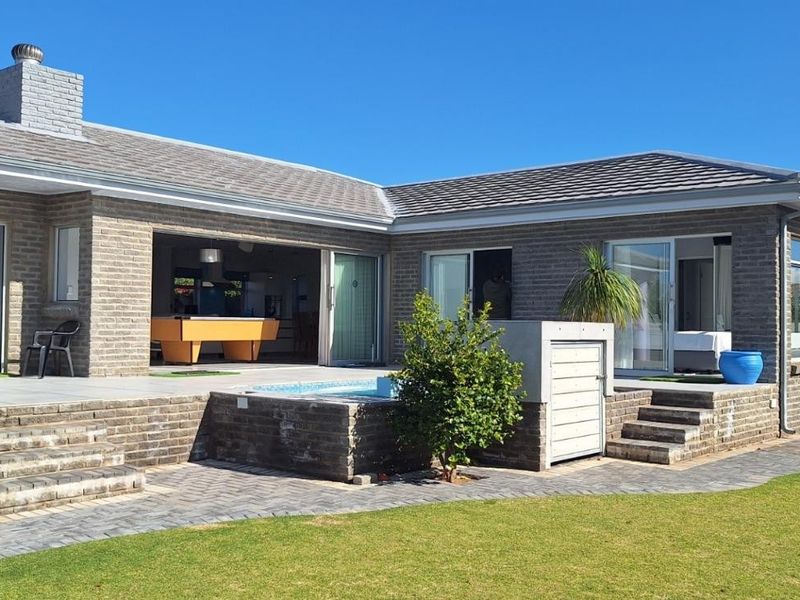 Rear view of the house featuring a paved patio, built-in brick steps, a small plunge pool, and sliding glass doors leading to the interior.