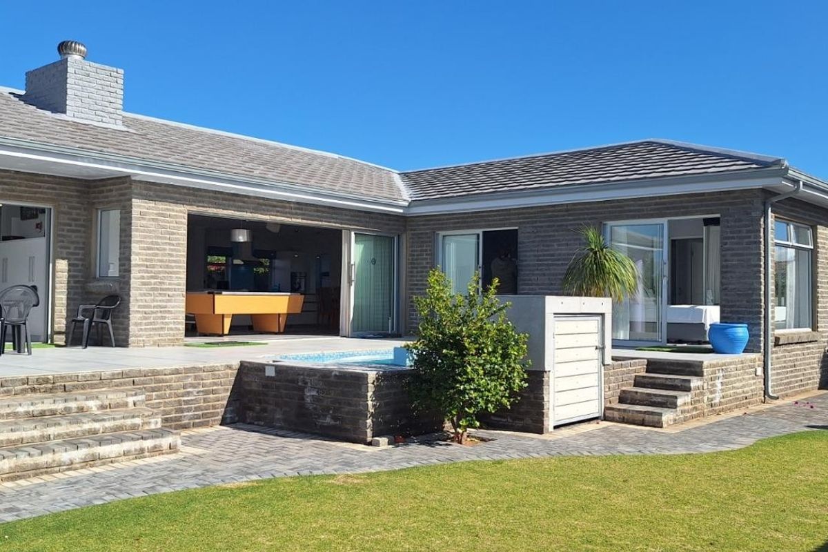 Rear view of the house featuring a paved patio, built-in brick steps, a small plunge pool, and sliding glass doors leading to the interior.