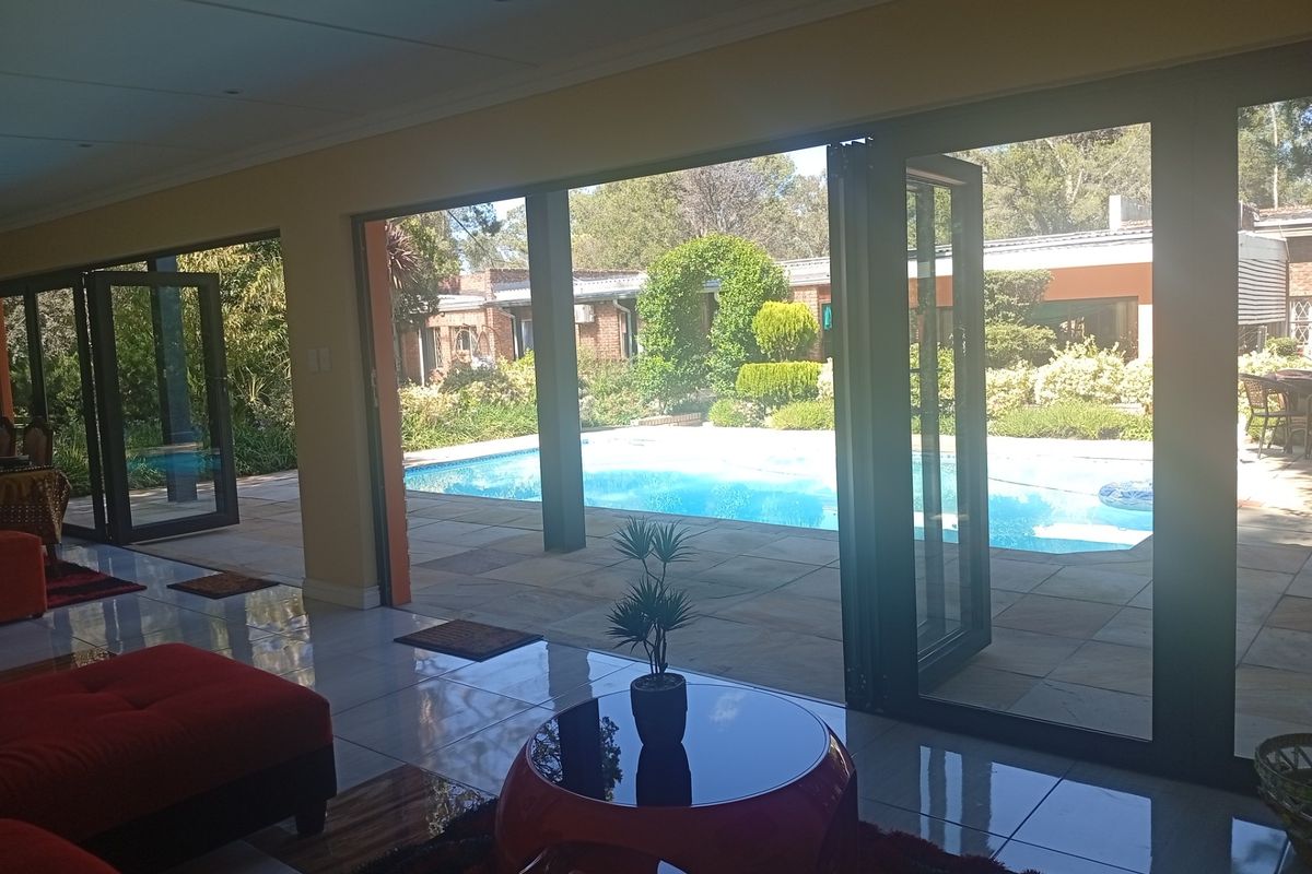 Spacious living area featuring large folding glass doors that open directly onto a paved patio and swimming pool area.
