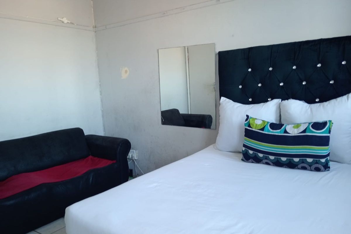 A bedroom featuring tiled flooring and a wall-mounted mirror, requiring minor cosmetic updates to the wall finishes.