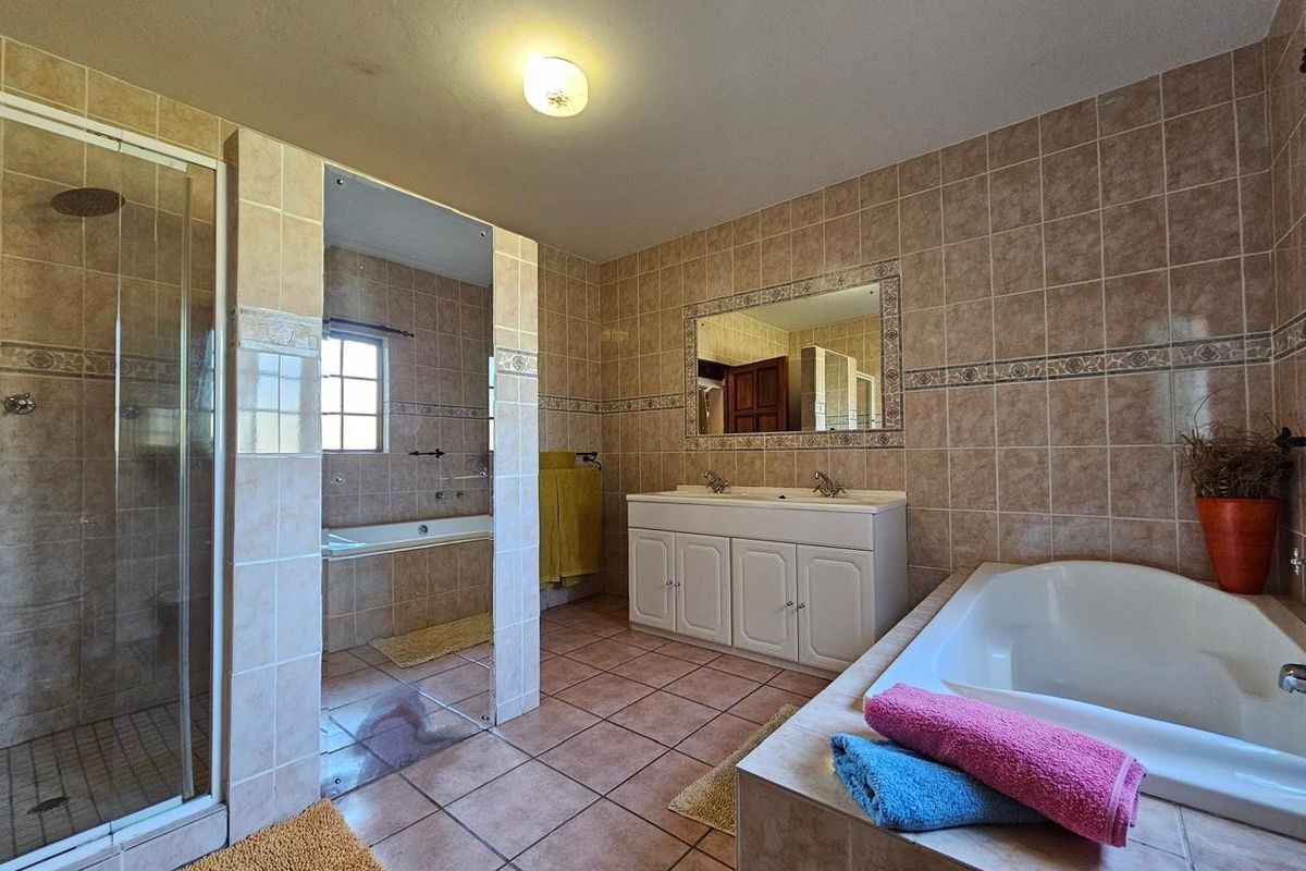 Spacious bathroom featuring a double vanity, separate shower enclosure, and a built-in bathtub with neutral wall and floor tiling.
