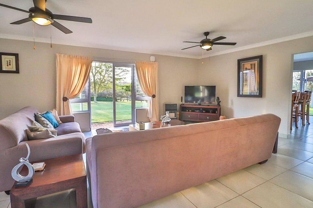 Spacious living room featuring tiled flooring, dual ceiling fans, and large sliding glass doors providing direct access to the rear garden.