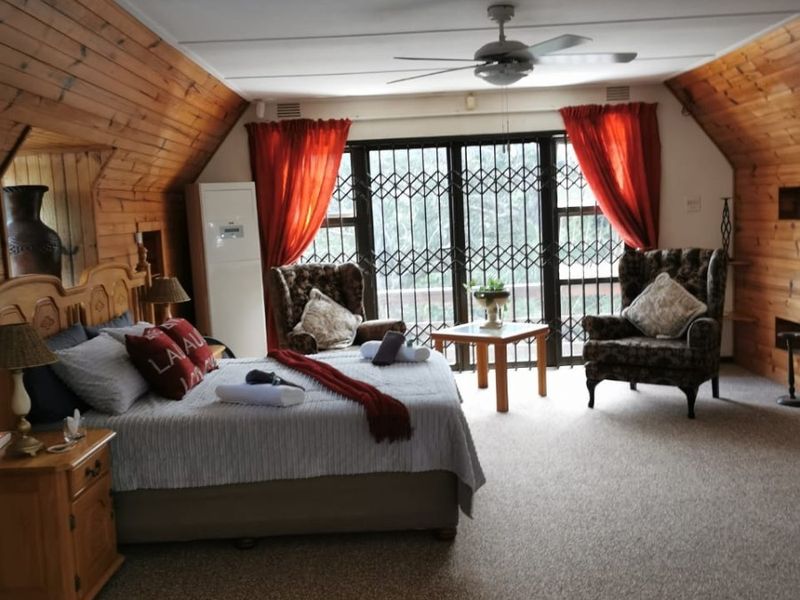 Spacious bedroom featuring vaulted ceilings with wood paneling, a ceiling fan, and large sliding doors with security gates leading to an outdoor area.