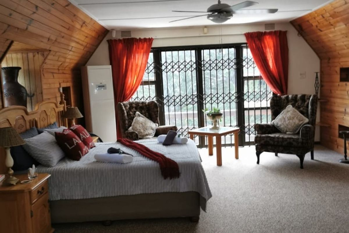Spacious bedroom featuring vaulted ceilings with wood paneling, a ceiling fan, and large sliding doors with security gates leading to an outdoor area.