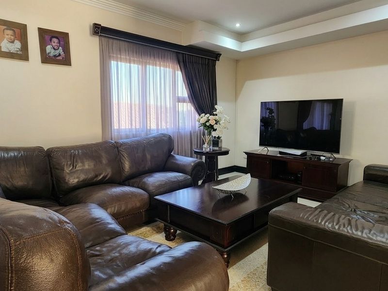 A comfortable living room featuring a recessed ceiling with downlights and large windows with curtain tracks, providing a functional and inviting space.