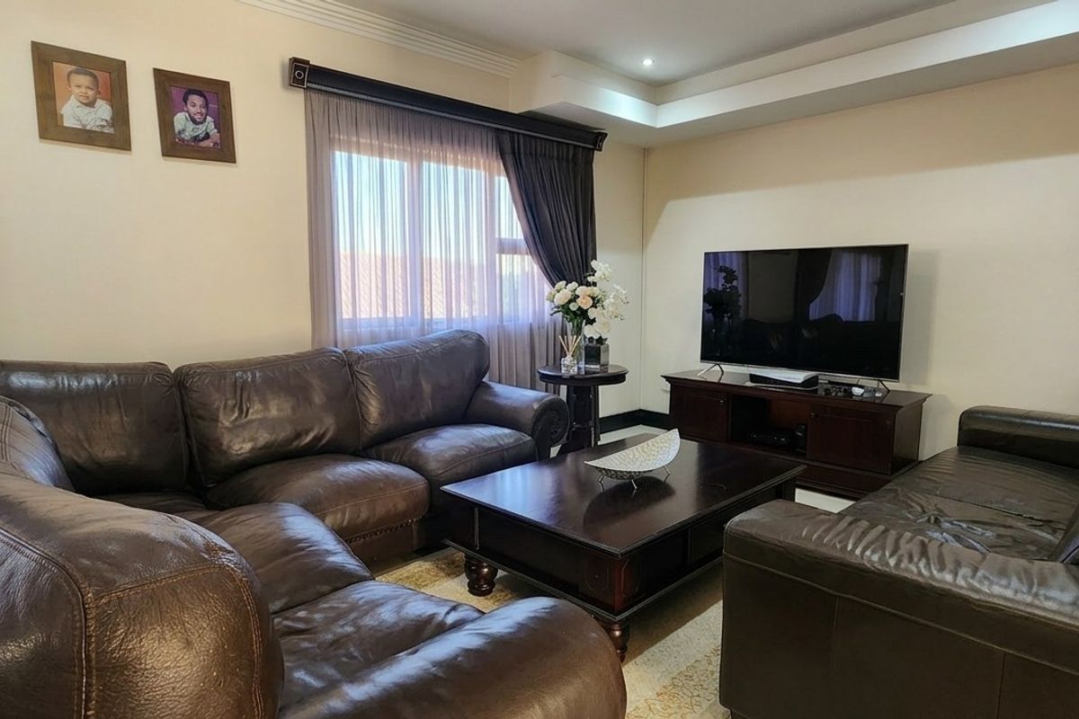 A comfortable living room featuring a recessed ceiling with downlights and large windows with curtain tracks, providing a functional and inviting space.