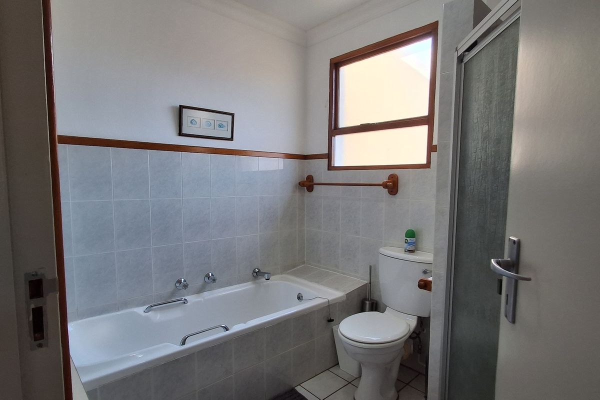A functional bathroom featuring a built-in bathtub, a standard toilet, and a separate shower enclosure with tiled walls.