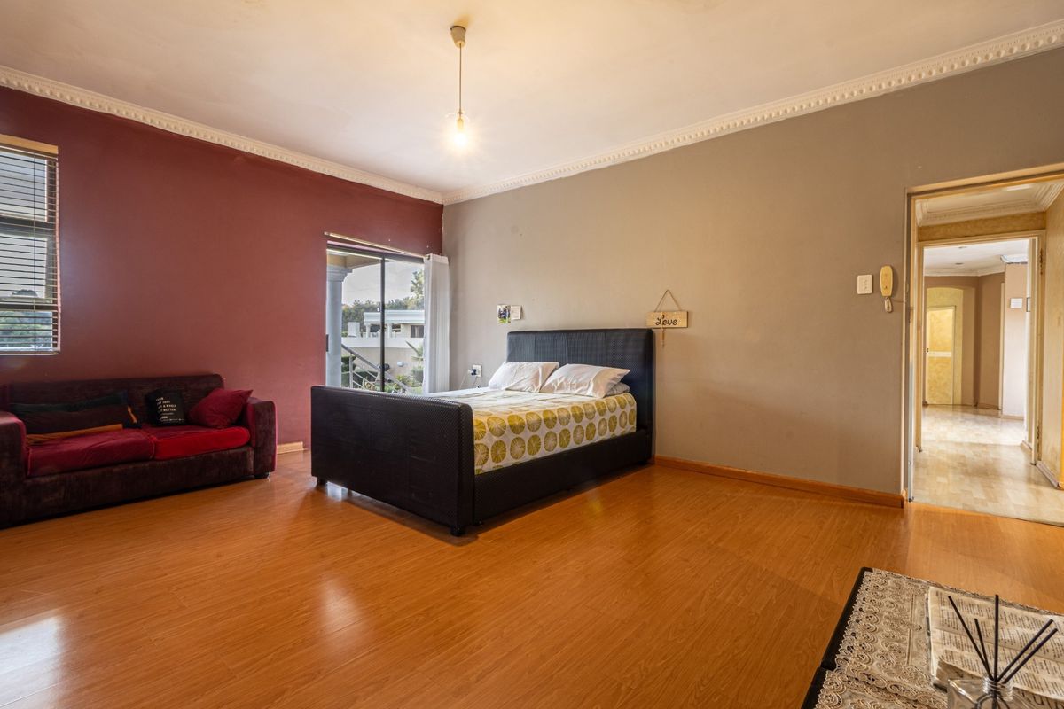 Spacious bedroom featuring laminate flooring, decorative ceiling cornices, and sliding glass doors providing access to an outdoor balcony area.