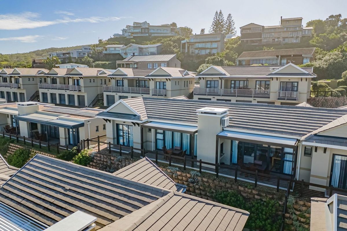 An elevated aerial view of a residential apartment complex featuring tiled roofs, private balconies, and landscaped terraced retaining walls.