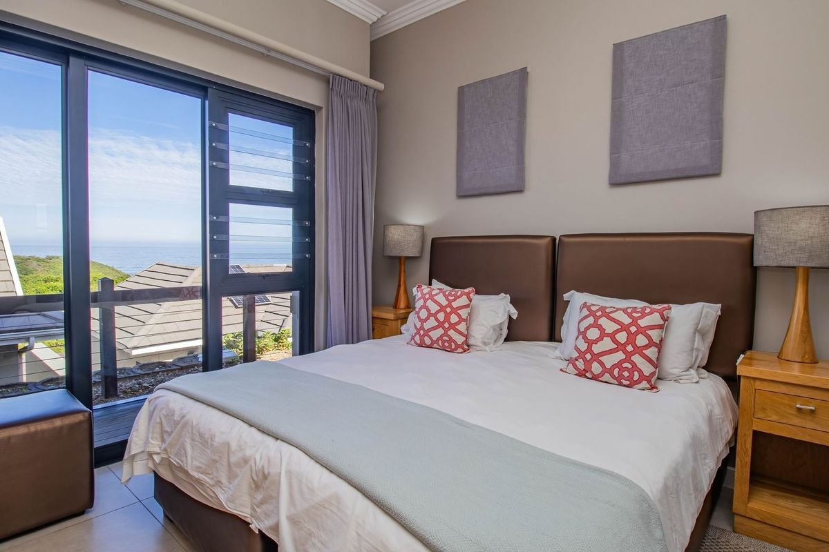 A well-maintained bedroom featuring large sliding glass doors that provide natural light and scenic coastal views.