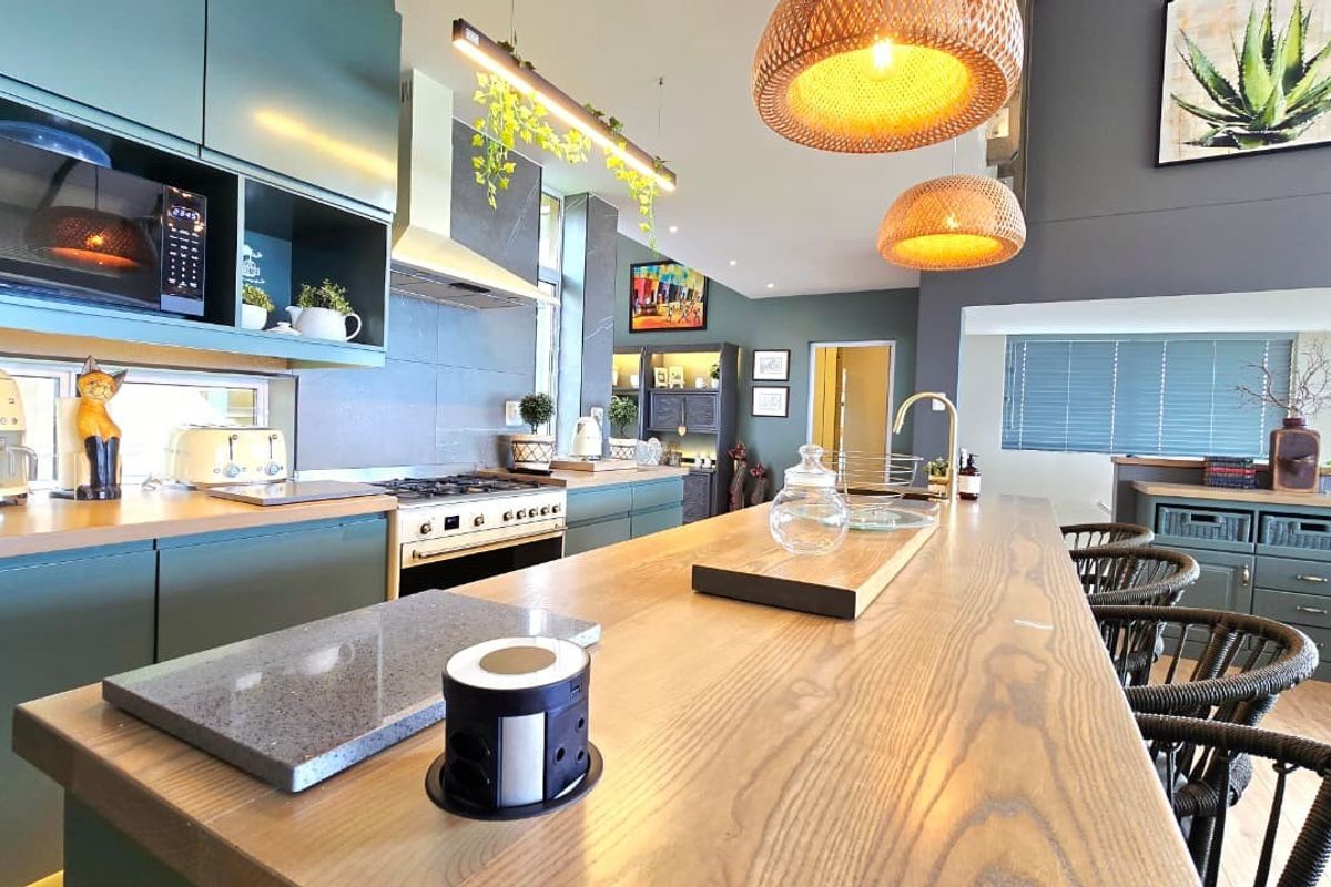 Modern kitchen featuring a large wooden island, sleek cabinetry, built-in appliances, and contemporary lighting, creating a functional and stylish culinary space.