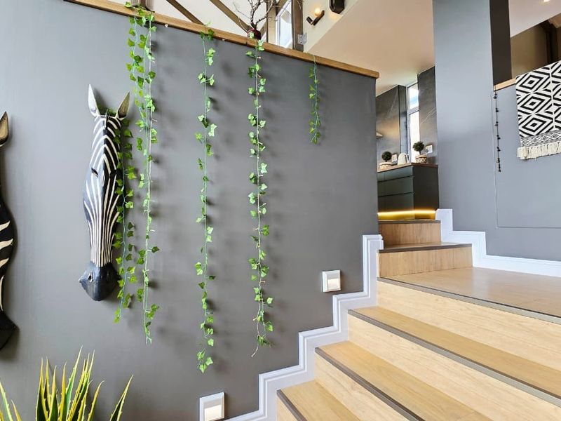 A modern hallway featuring a staircase with wooden treads, a timber handrail, and integrated recessed wall lighting, creating a contemporary and well-lit transition space.