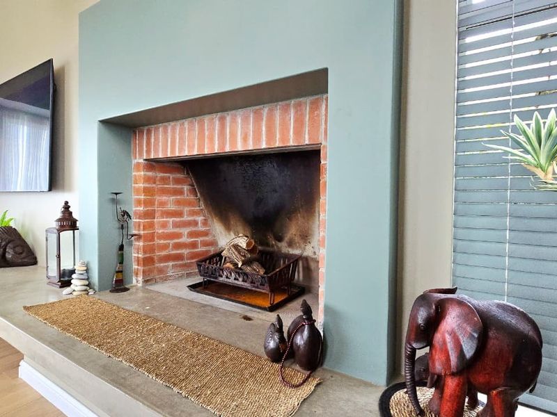 A cozy living room featuring a prominent built-in fireplace with an exposed brick firebox and a sleek concrete hearth.