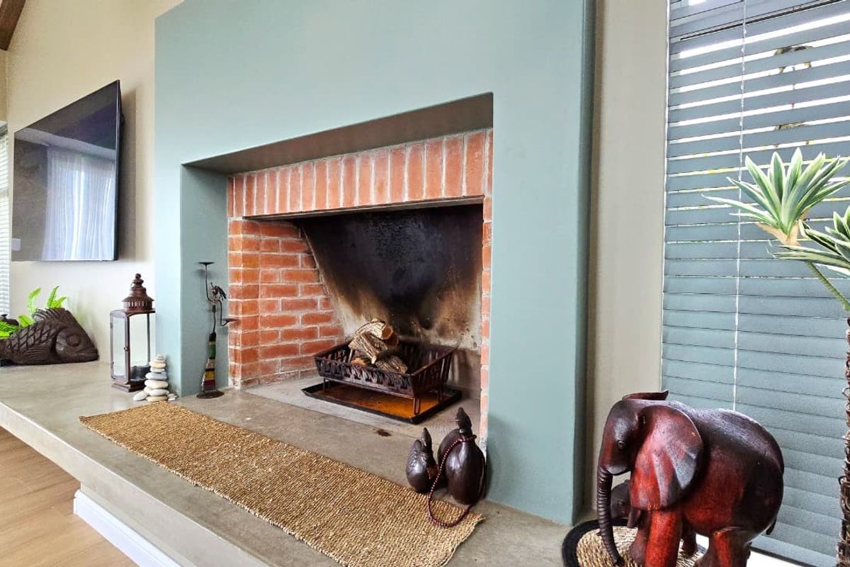 A cozy living room featuring a prominent built-in fireplace with an exposed brick firebox and a sleek concrete hearth.