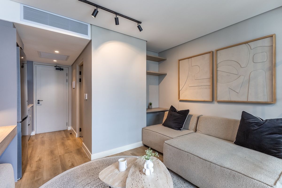 A modern, well-maintained living area featuring sleek track lighting, ducted air conditioning, and built-in shelving, finished with high-quality laminate flooring.