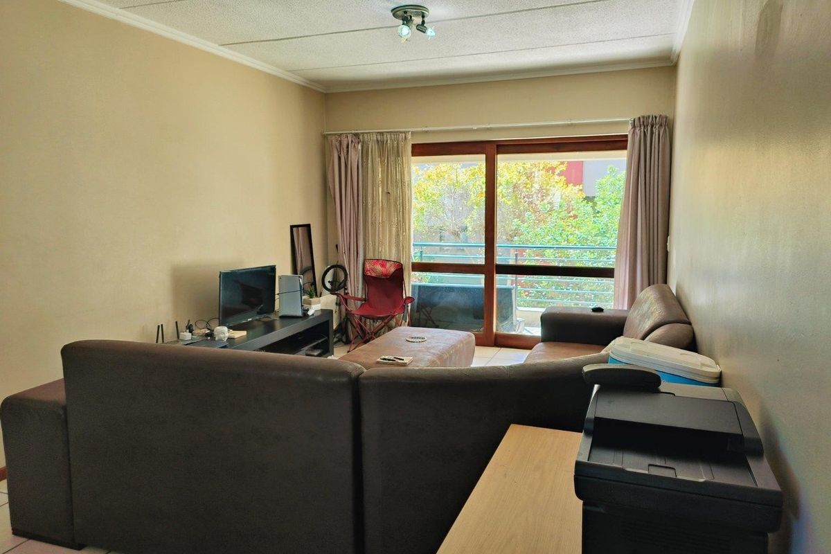 A living room featuring tiled flooring and large sliding glass doors that provide access to an outdoor balcony area.
