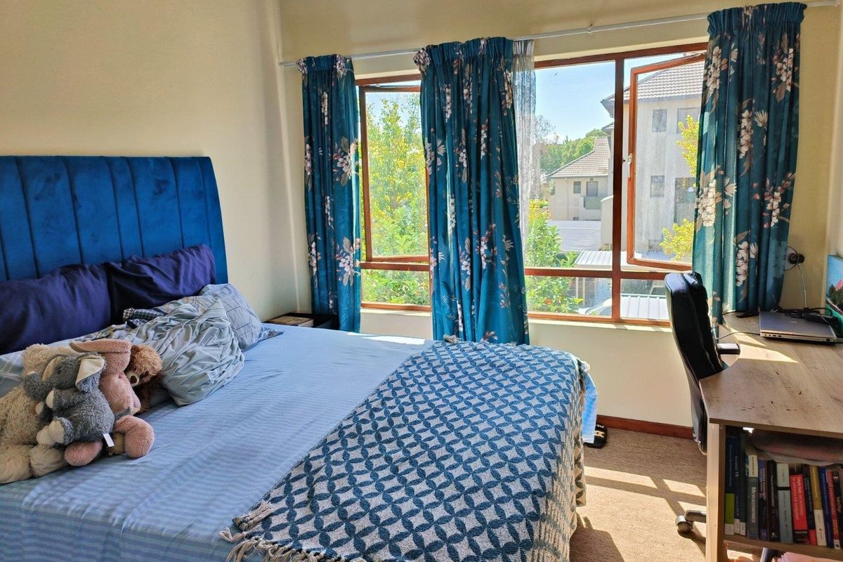 A bedroom featuring large windows that provide natural light and a view of the surrounding neighborhood.