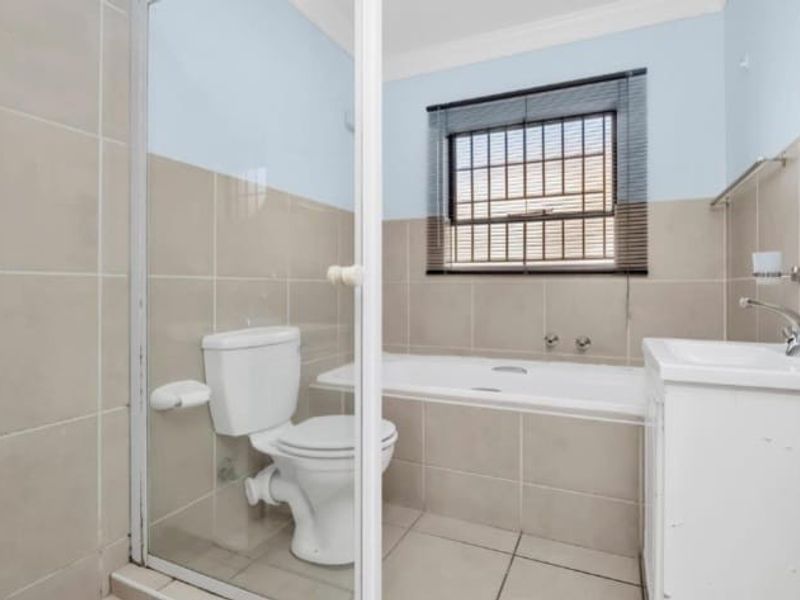 A functional bathroom featuring a built-in bathtub, a separate shower enclosure, and a vanity basin with tiled walls and flooring.