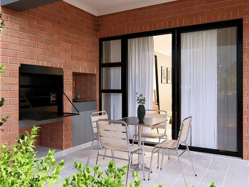 A covered patio featuring a built-in brick braai and large sliding glass doors providing seamless access to the interior living space.