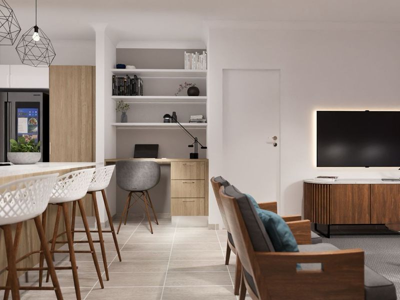 Modern open-plan living area featuring a sleek kitchen with breakfast bar, integrated appliances, and a dedicated built-in study nook with shelving.