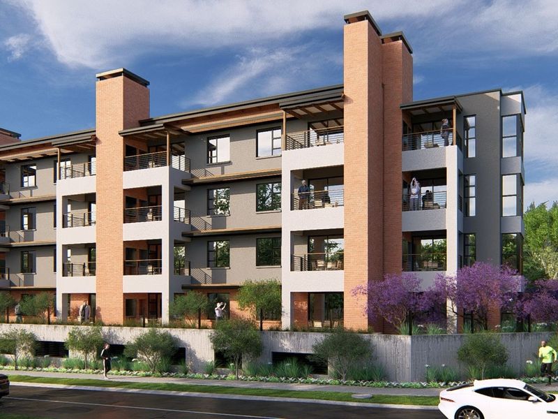 A modern multi-story apartment building featuring brick chimneys, private balconies with metal railings, and a landscaped street-level perimeter.