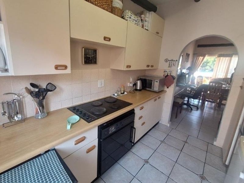 A functional kitchen featuring built-in cabinetry, an electric hob, and an oven, with an arched opening leading to the adjacent living area.