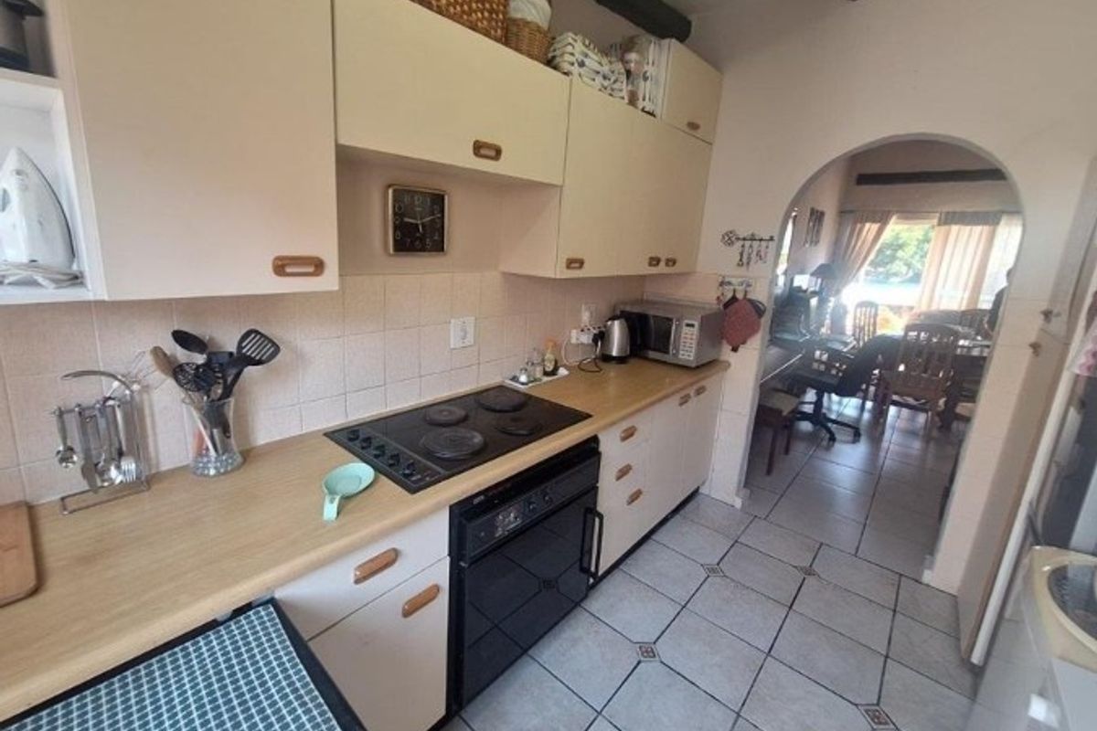 A functional kitchen featuring built-in cabinetry, an electric hob, and an oven, with an arched opening leading to the adjacent living area.