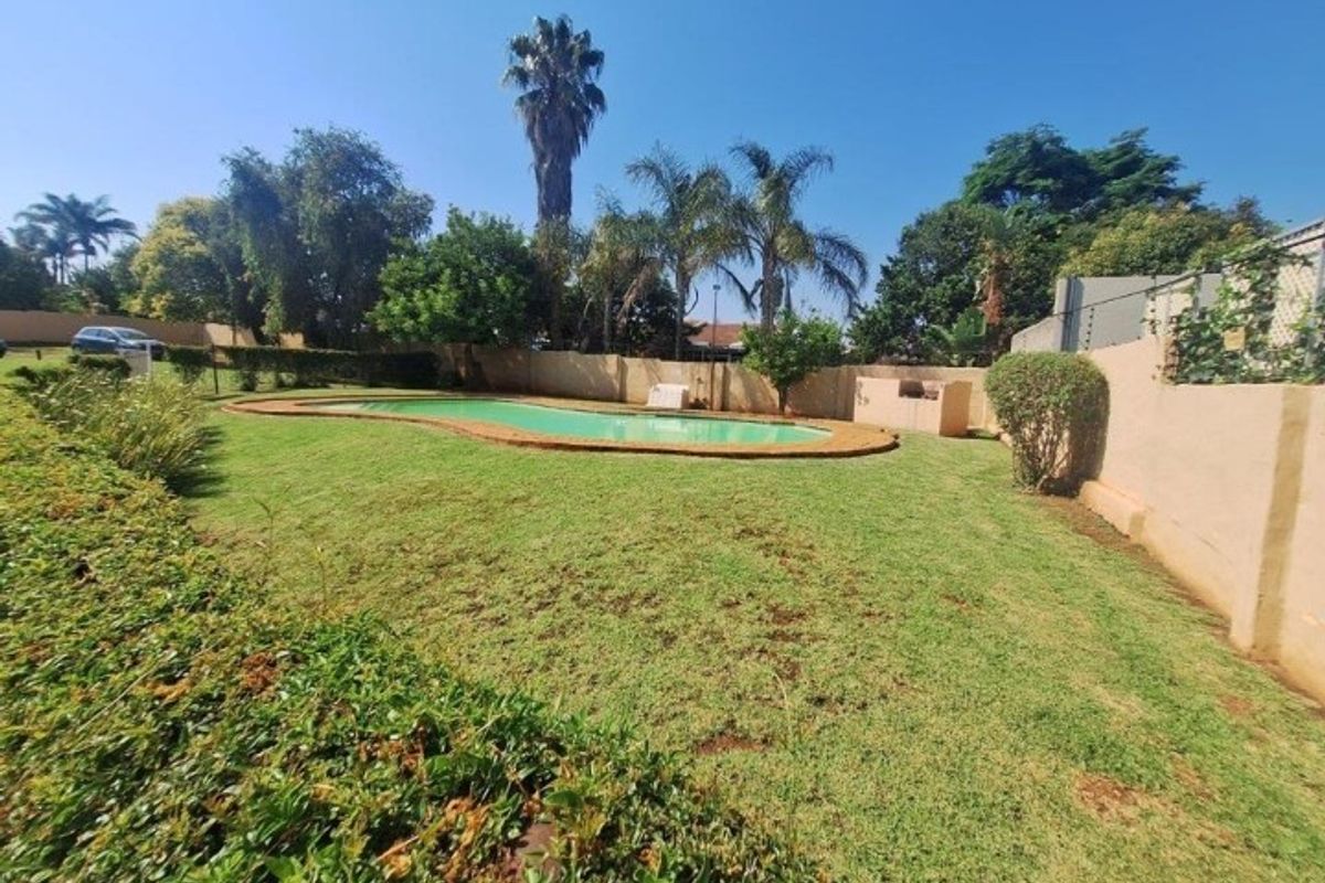 Spacious backyard featuring a swimming pool, built-in braai area, and established lawn enclosed by perimeter walls.