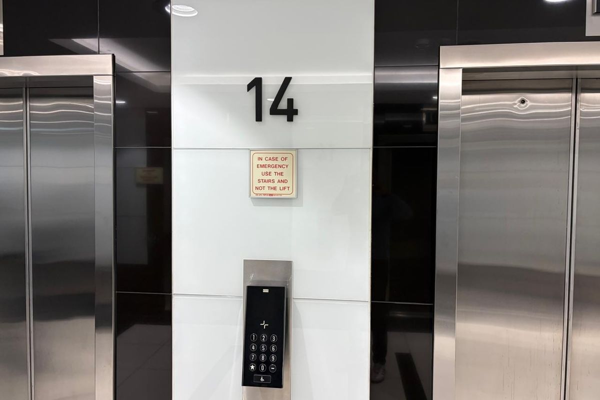 Modern office building elevator lobby on the 14th floor featuring stainless steel lift doors and a digital access control keypad.