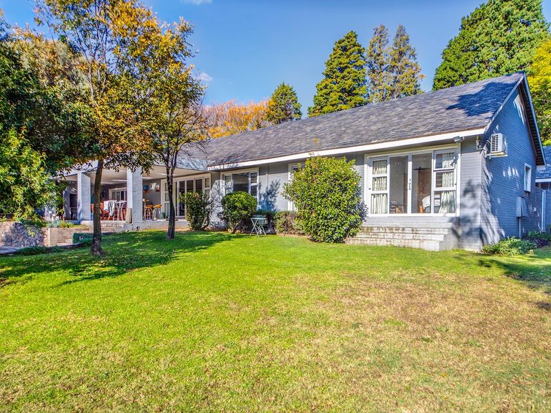 Rear view of the house featuring a spacious lawn, covered patio area, and large sliding glass doors leading into the home.