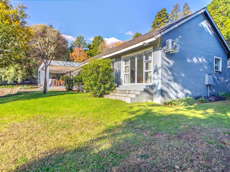 Rear view of the house featuring a painted brick facade, sliding glass doors, an outdoor patio area, and a well-maintained garden.