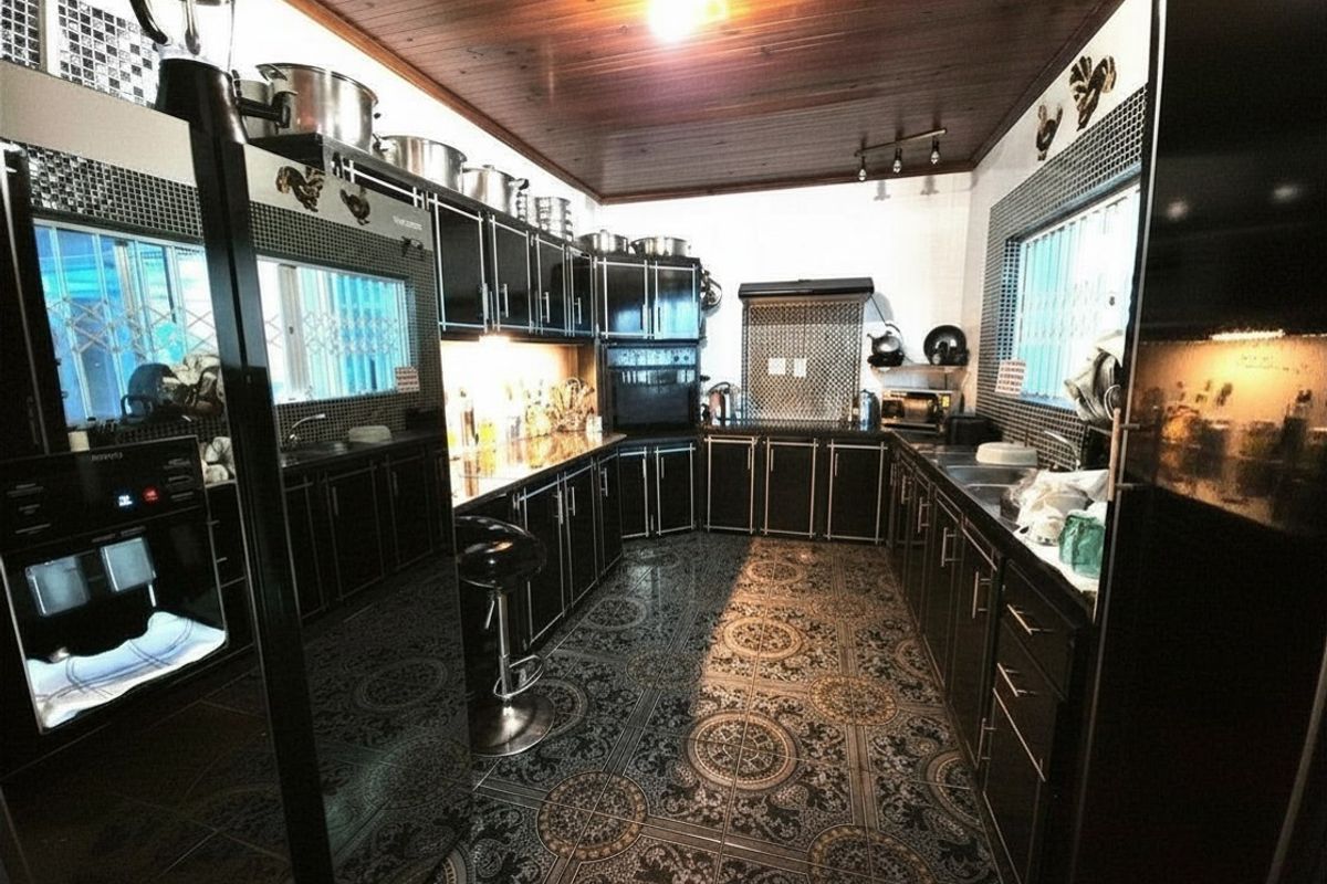 A spacious kitchen featuring dark cabinetry, patterned floor tiles, a wooden ceiling, and integrated appliances, offering a functional and distinct culinary workspace.