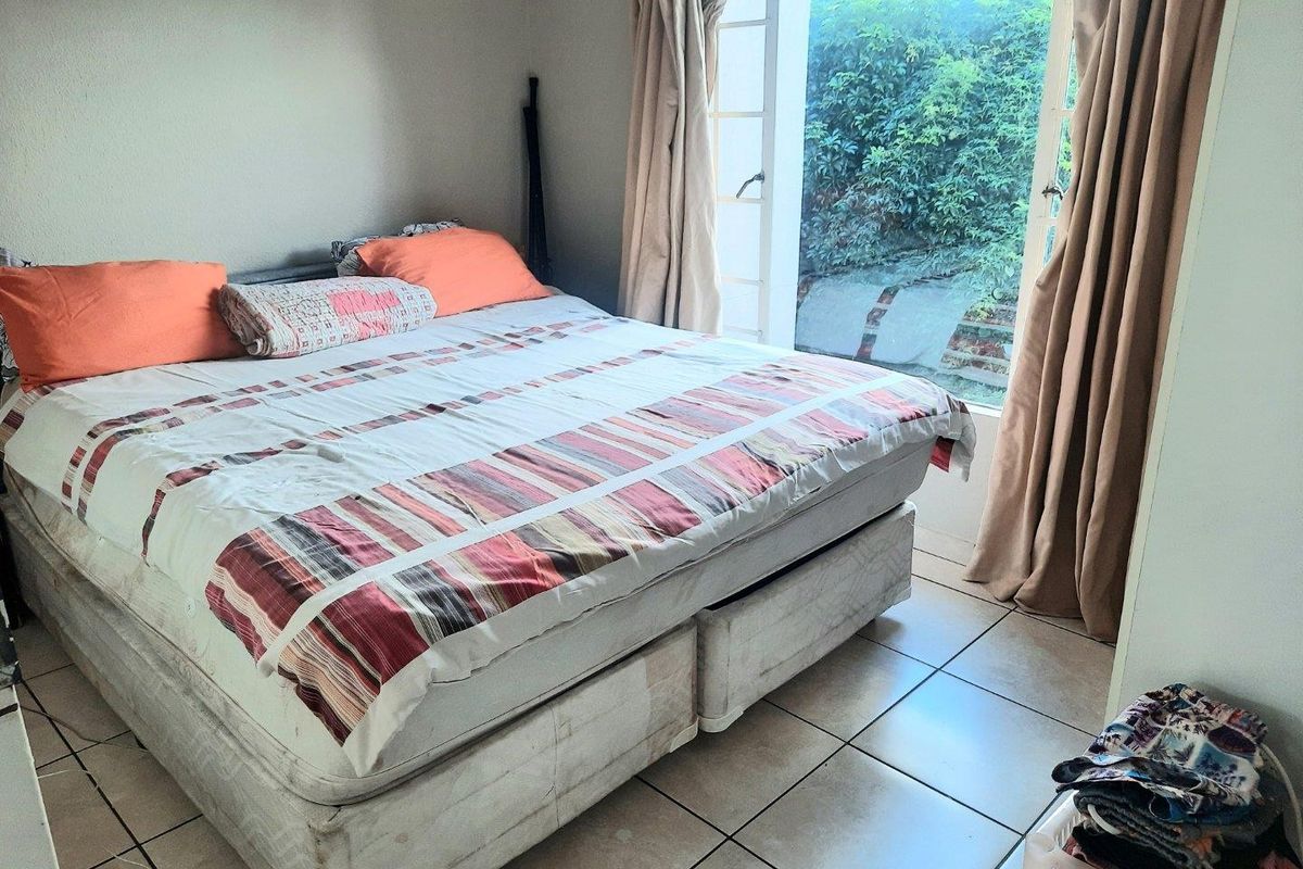 A bedroom featuring tiled flooring and direct access to an outdoor area through a glass door.