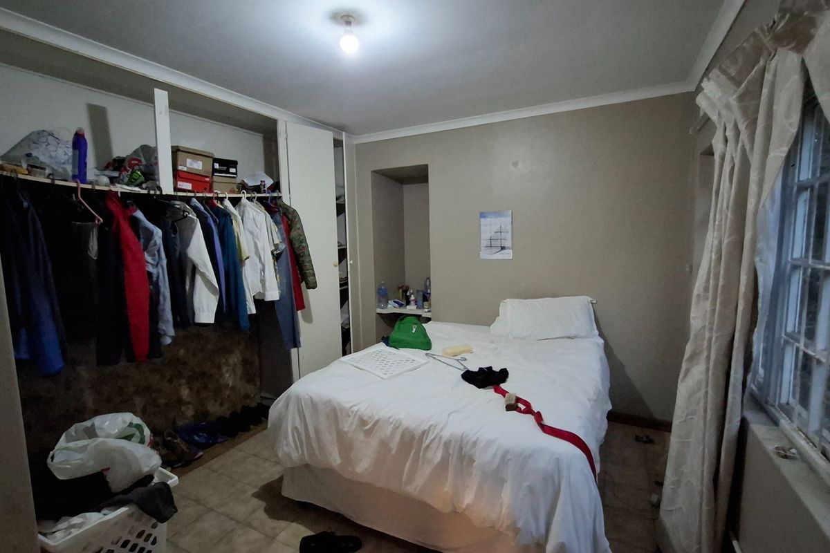 A bedroom featuring built-in closet space with open shelving and tiled flooring, offering a functional layout with potential for cosmetic updates.
