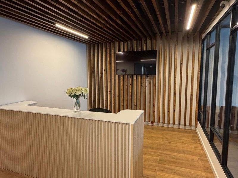 Modern office reception area featuring a custom slatted wood feature wall, integrated linear lighting, and a sleek built-in reception desk.