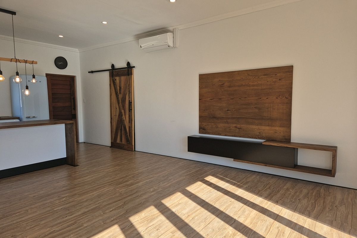 Modern living area featuring timber-look flooring, a sliding barn door, and a custom built-in media console with integrated wall paneling.