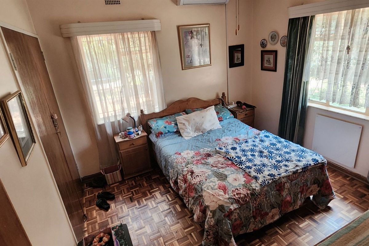 A cozy bedroom featuring classic parquet flooring, built-in wooden cupboards, and an integrated air conditioning unit for climate control.
