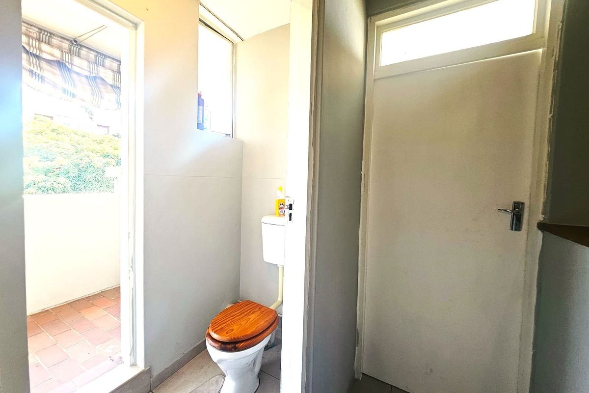 A functional bathroom featuring a standard toilet and direct access to an outdoor balcony area.